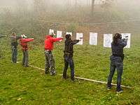 A line of people aiming at targets.