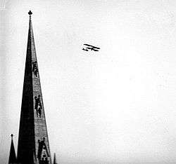 Cathedral spire with biplane in level flight in the distance