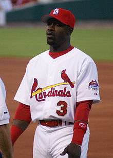 A man in a white baseball uniform with "Cardinals" and "3" on the chest wearing red cap and armbands.