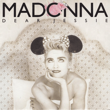 Sepia image of a blond woman sitting on a bed, holding the bedsheet to her bosom. She wears a headdress with a large bow, and two black round structures on either side. The woman looks towards the top, where the word "Madonna" is written in capital font. A pink elephant is squeezed inside the letter "O" of Madonna, beneath which "Dear Jessie" is written.