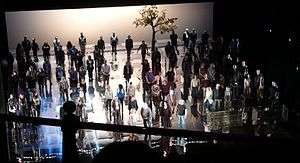 shot from theatre auditorium of performers grouped symmetrically on the stage