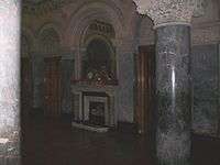 Picture of Dobroyd Castle's Saloon showing the marble pillars, clock, arched mirror and fireplace.