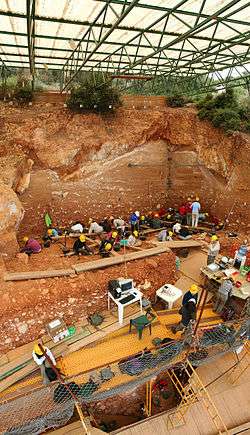 Archaeological excavation site in red earth.