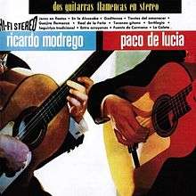 Two men playing flamenco guitars. It only shows their hands and the guitars.