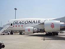 An aircraft in white colour, with the name Dragonair Cargo and Dragonair's Chinese name on its fuselage, parked on the tarmac.