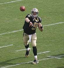 A light-skinned man throwing a football