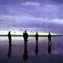An album cover showing four men in silhouette standing on a wet beach. There are dark clouds in the sky and the sun is low on the horizon. The album's name and the band's name is in white letters in the top centre of the album cover.