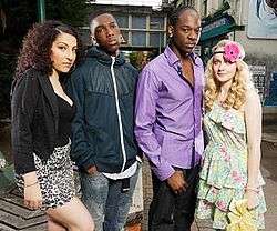 Naz, a woman of Turkish ethnicity, has heavy make-up on her face. She is wearing a short, leopard print skirt, low-cut black top and a black jacket. Standing next to her is Sol, a black man wearing a blue jacket and blue jeans, with his hands in his pockets. Another black man, Asher, is next to Sol, and wears a purple shirt with the top few buttons open. Finally, Stevie is next to Asher. She has blonde hair in curls, and is wearing a light, flowery dress and a headband with a large pink flower on it.