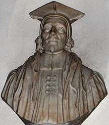 A stone bust of a man (head and shoulders), with beard, cap and robes