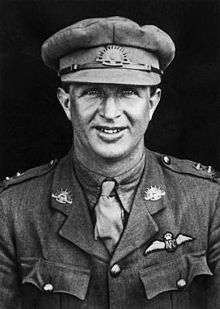 Half portrait of man in military uniform with peaked cap and pilot's wings on chest