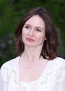 Picture of Emily Mortimer dressed in white against a green background