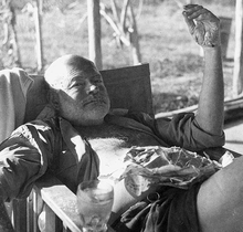 photograph of Ernest Hemingway relaxing in a camp chair at the fishing camp in Africa