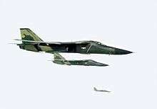 Two green jet aircraft flying together, right of wing. Further out in the background is another jet aircraft.