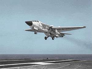White variable geometry-wing jet aircraft landing on carrier