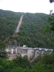 Power station next to a river dam, with two steel tubes bringing water from a unseen lake 500m above.