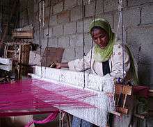 An Ethiopian woman, a member of FWFCA, working at a loom