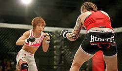 Two female fighters prepared to strike at each other while standing.