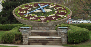 A large clock whose face, made from flowers, bears the outline of the state of Kentucky and the word "Kentucky"