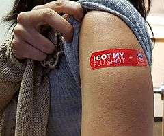 A young woman shows off her flu shot after receiving vaccine at a local drug store.