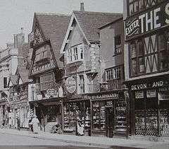 Old photograph of Tudor building with wooden buildings in the protruding upper floors.