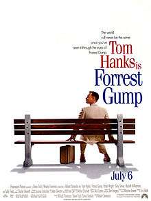 Film poster with an all-white background, and a park bench (facing away from the viewer) near the bottom. A man wearing a white suit is sitting on the right side of the bench and is looking to his left while resting his hands on both sides of him on the bench. A suitcase is sitting on the ground, and the man is wearing tennis shoes. At the top left of the image is the film's tagline and title, and at the bottom is the release date and production credits.