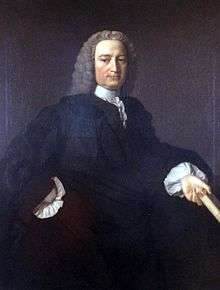 A colour painting of a man with white hair that may be a wig, in a dark gown with white sleeves and collar, he holds a book in his hand.