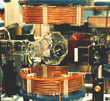 A complex experimental setup featuring a horizontal glass tube placed between two copper coils.