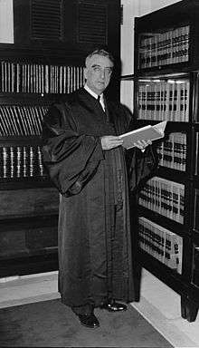 A formal portrait of an older man, sitting, in judicial robes