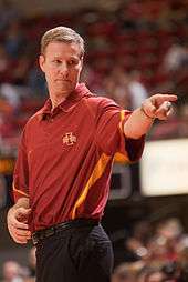 Fred Hoiberg in a red Iowa State polo shirt tucked into black pants