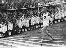 Athlete running down steps holding the Olympic torch