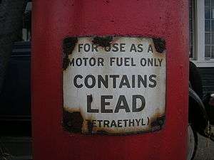 a closeup of a red gasoline pump with a warning label that reads, "for use as a motor fuel only" (in larger writing) "contains lead" (in smaller writing) "(tetraethyl)"