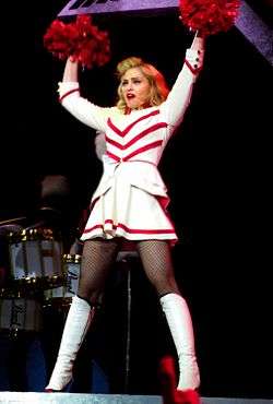 Madonna in a white and red dress performing, with pom-poms in her hand