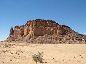 A large, square-shaped mound made up of dirt and rock in the middle of a deserted area.