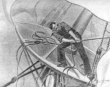 Illustration of a man with dark hair and wearing a sailor suit, standing on a platform attached to a ship's mast and pulling strenuously on a rope. The platform and mast are severely tilted to the right, and sails, pulleys and other ropes can be seen.