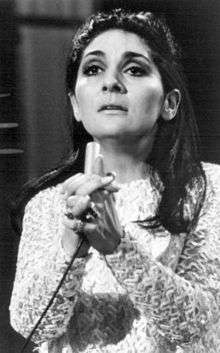 A black and white photograph of a caucasian woman with dark hair clasping her hands together.