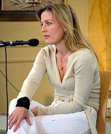 A blonde woman seated in front of a microphone