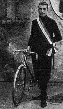 A man standing while holding a bike upright.