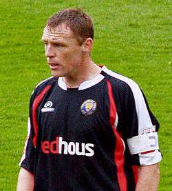 A man wearing a black, red and white football shirt.