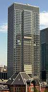 Mid-level view of a rectangular, glass high-rise; one side is vertically bisected by a section