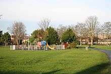 small park with tower blocks along the horizon. A bright childen's playground dominates