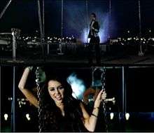 The top of the image shows a man with gelled, black hair, a white tee shirt, jeans and a black leather jacket that stands behind a swing at nighttime. The bottom of the image shows a teenage female with long, brunette hair facing forward as she grasps chains with both of her hands.