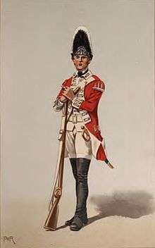 Print shows a standing soldier in a red coat with black gaiters and white breeches, turnbacks, and waistcoat. The soldier holds a musket and wears a tall bearskin hat.