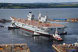 A Queen Elizabeth-class aircraft carrier docked in Scotland. This ship is one of two planned aircraft carriers and will soon make its way to Portsmouth Harbour, its home port.
