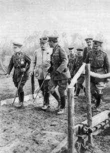 Two British and one French General leading a group of four British officers across a small wooden bridge