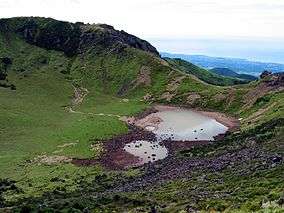 View into an inactive volcanic crater with a small like.