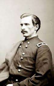 Profile of a white man with mustache wearing a double-breasted military jacket with one star on a patch on the shoulder.
