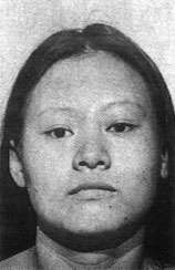 Mugshot of a woman: her face is broad and squarish, framed by long hair.