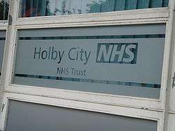 A partially frosted window pane, inscribed with the words 'Holby City NHS, NHS Trust'