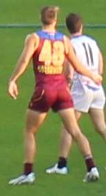 A man in a maroon jersey wearing number 48 stands on grass next to a man in a white jersey wearing number 11.