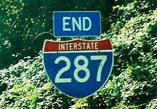 An end I-287 shield with trees in the background